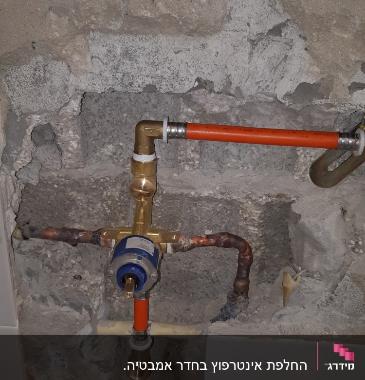 צנרת מים חשופה עם חיבורים וברזים בקיר